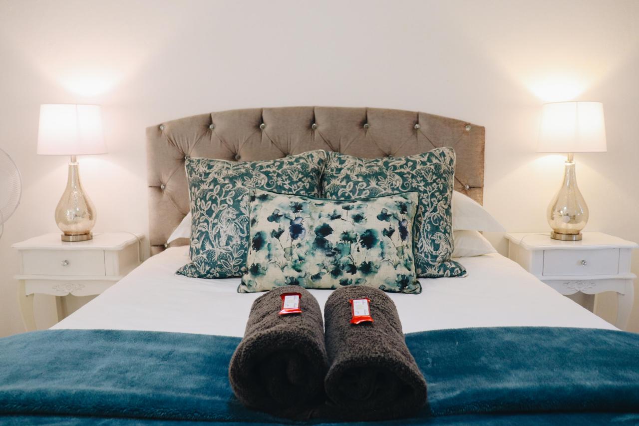 Main bedroom with tufted headboard and mountain-facing window at Sipreslaan Selfsorg Gastehuis
