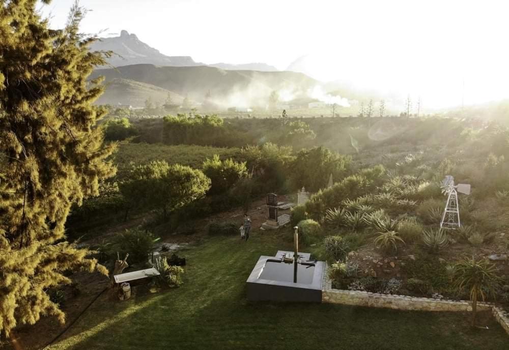 Aerial view at dusk of the garden, wood-fired hot tub and windmill at Sipreslaan Selfsorg Gastehuis
